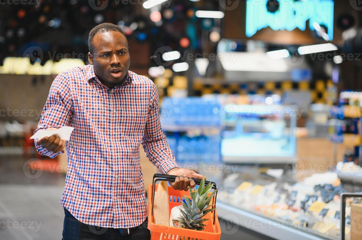 verrast Afro-Amerikaans Mens looks Bij bon totaal in verkoop controleren Holding papier zak foto