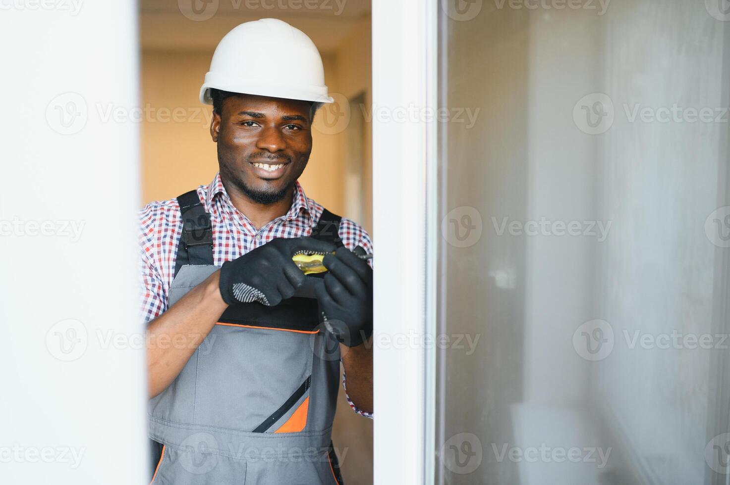 jong Afrikaanse klusjesman in uniform vaststelling glas venster met schroevedraaier foto