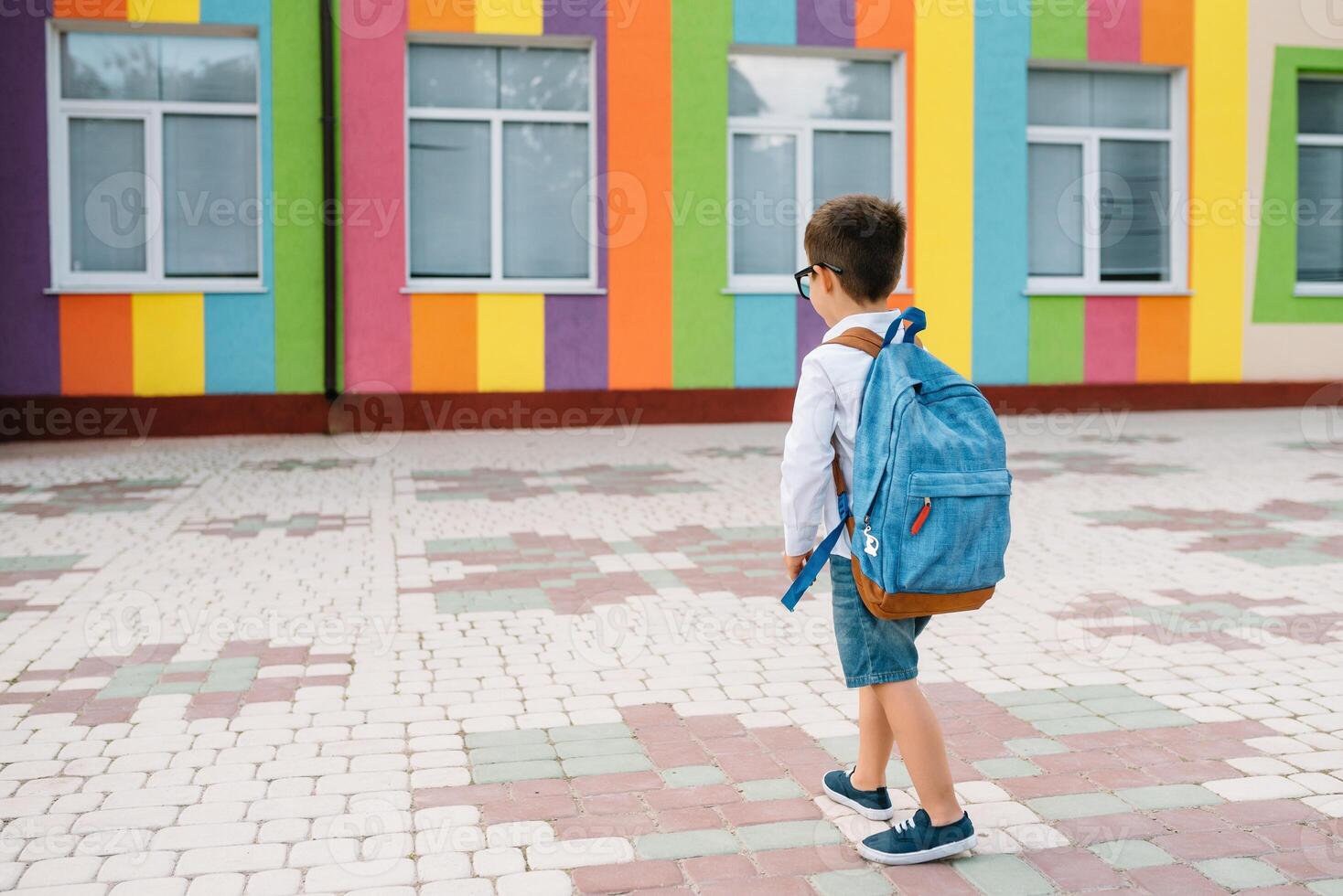 weinig jongen gaan terug naar school. kind met rugzak en boeken Aan eerste school- dag. terug visie. school- concept. terug naar school. foto