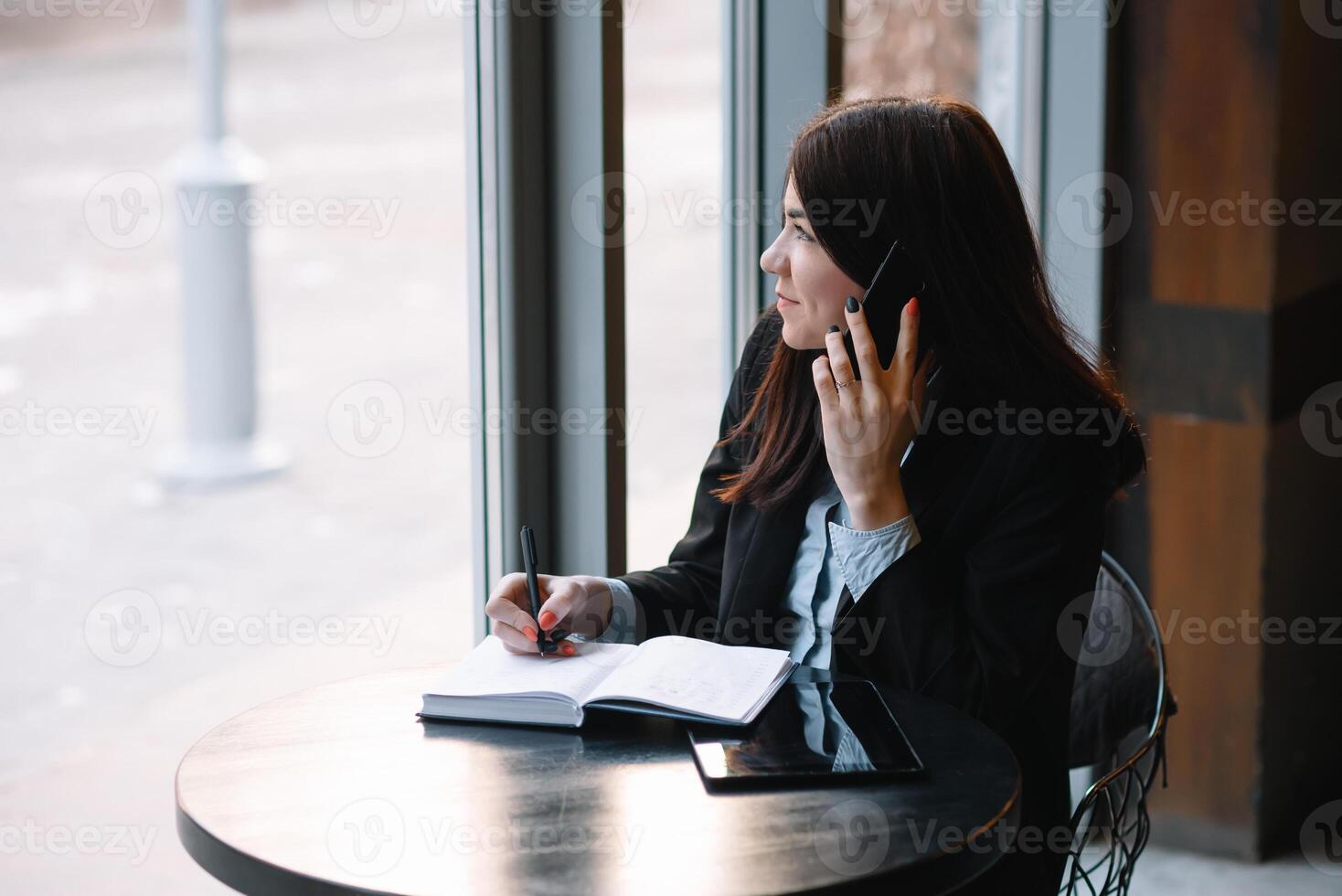 zakenvrouw pratend Aan de telefoon en nemen aantekeningen foto