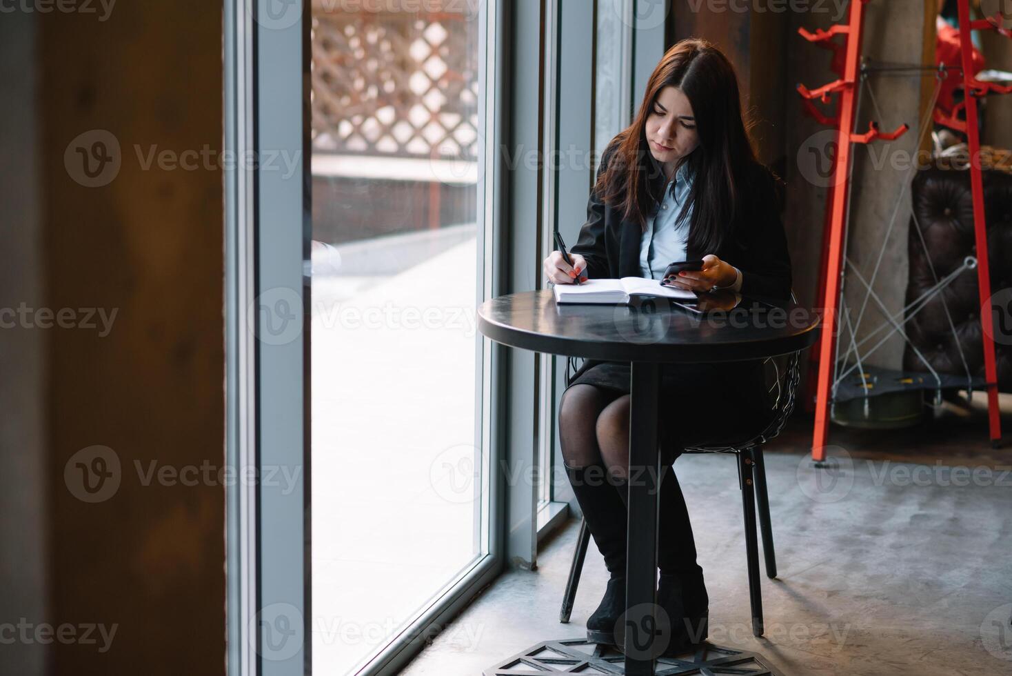 zakenvrouw pratend Aan de telefoon en nemen aantekeningen foto