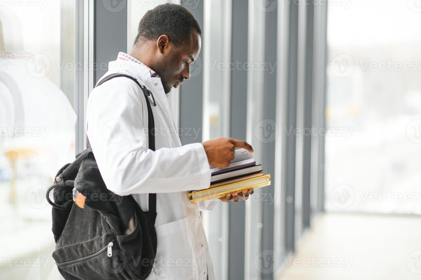 portret van medisch leerling. jong Afrikaanse Amerikaans dokter lezen boek, en documenten voorbereidingen treffen voor examens foto