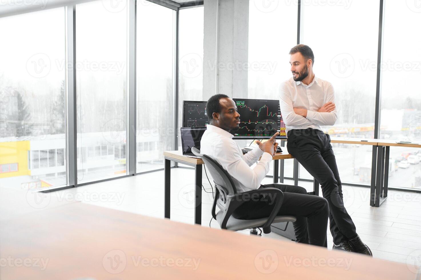twee mannen collega's handelaren zittend Bij bureau Bij kantoor toezicht houden voorraad markt foto