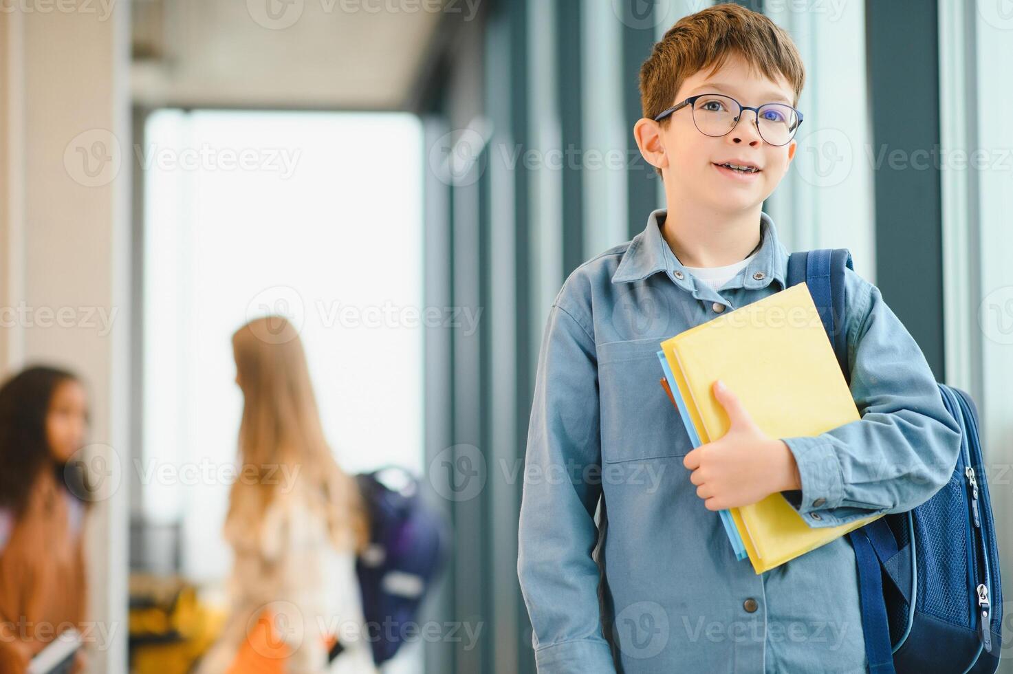 schooljongen met schooltas en boeken in de school. onderwijs concept. terug naar school. schoolkind gaan naar klas. elegant jongen met rugzak. jongen klaar naar studie foto