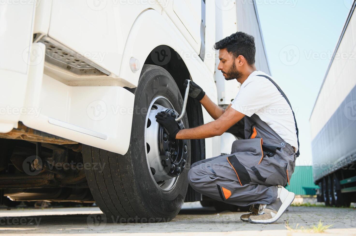 Indisch monteur draait los wiel vrachtauto pneumatisch moersleutel foto