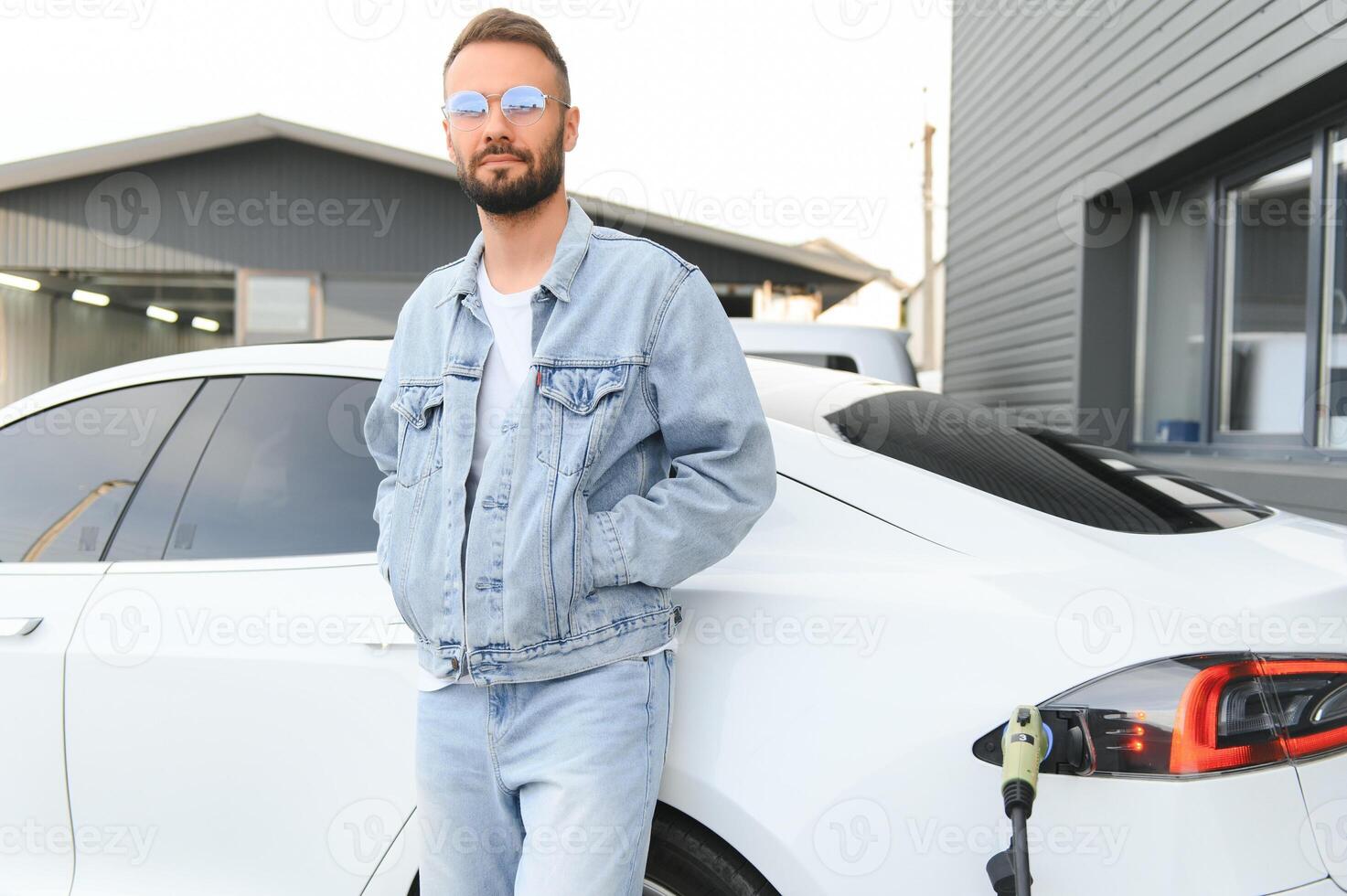 Mens opladen elektrisch auto door de huis. foto