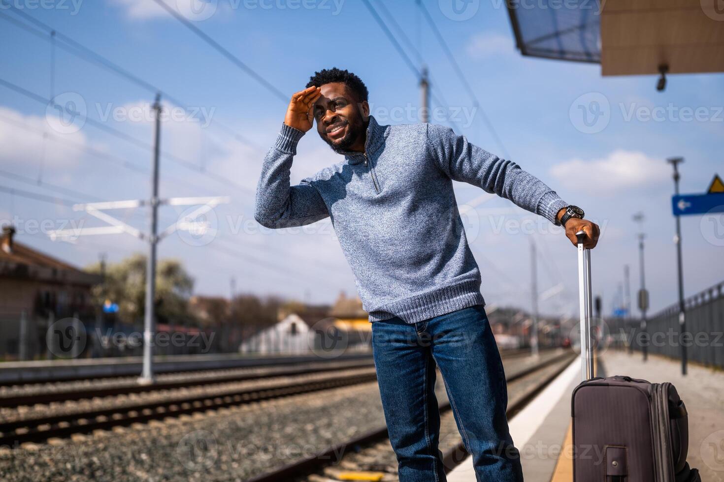 gelukkig Mens op zoek weg terwijl staand Aan een spoorweg station. foto