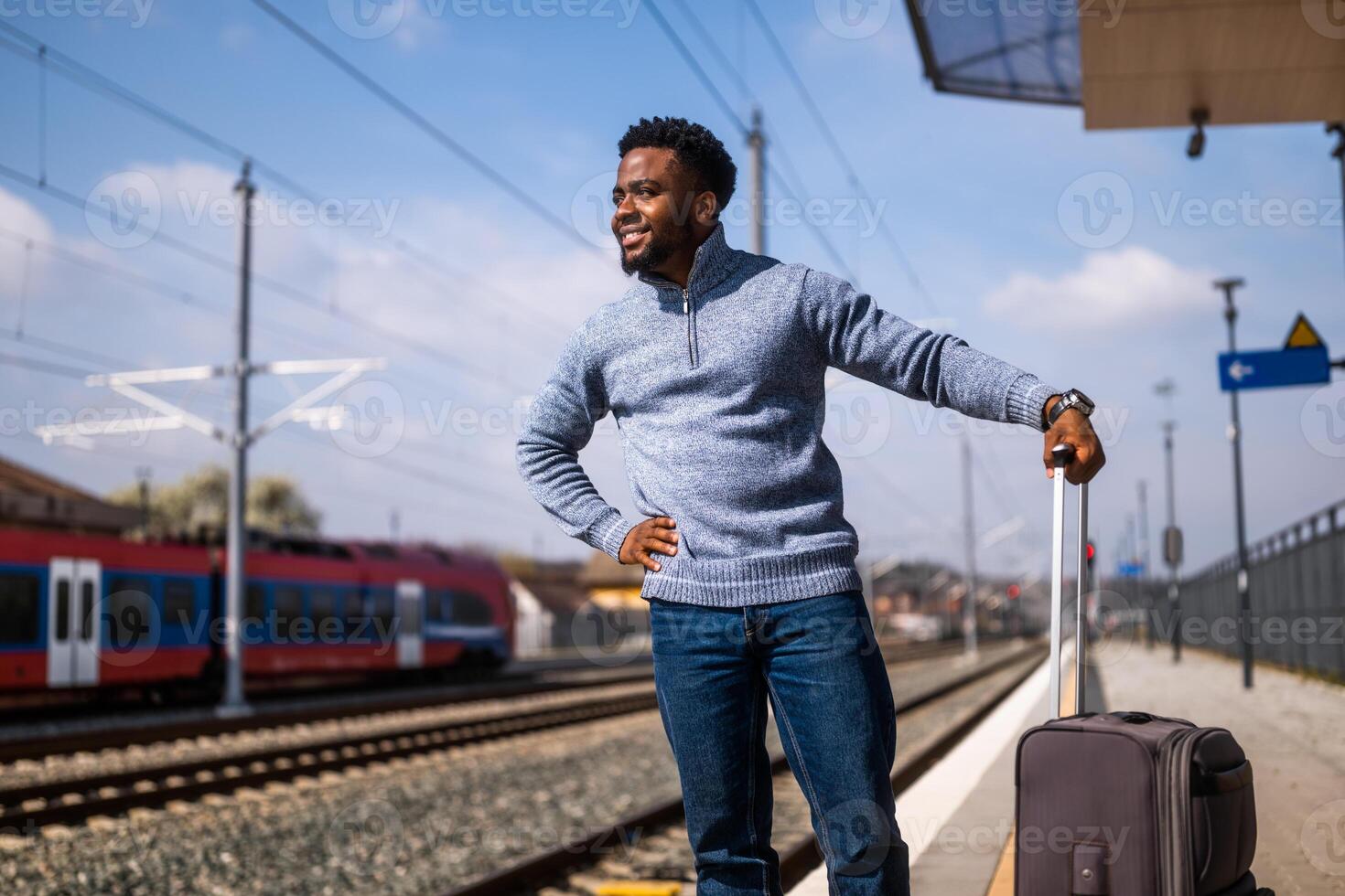 gelukkig Mens met koffer staand Aan spoorweg station foto