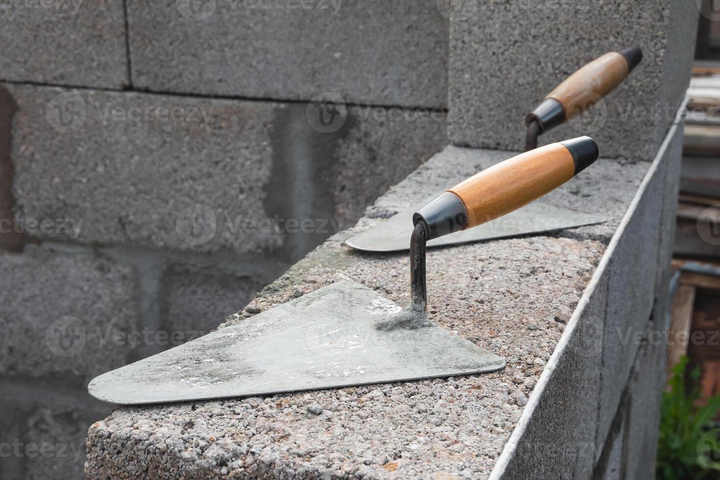 de beton arbeiders troffels liggen Aan een sintel blok bouw steen. het is gebruikt voor metselen, net zo goed net zo voor meten en toepassen cement Mortier foto