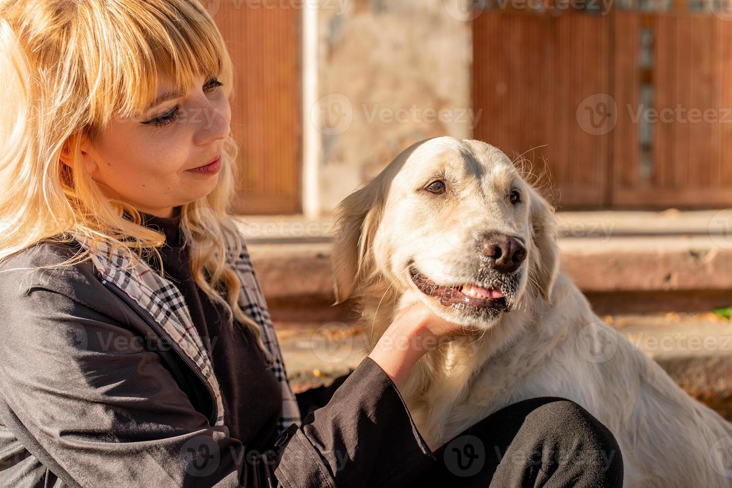 gelukkige blanke vrouw die geniet van tijd met haar labrador retriever-hond in het park foto