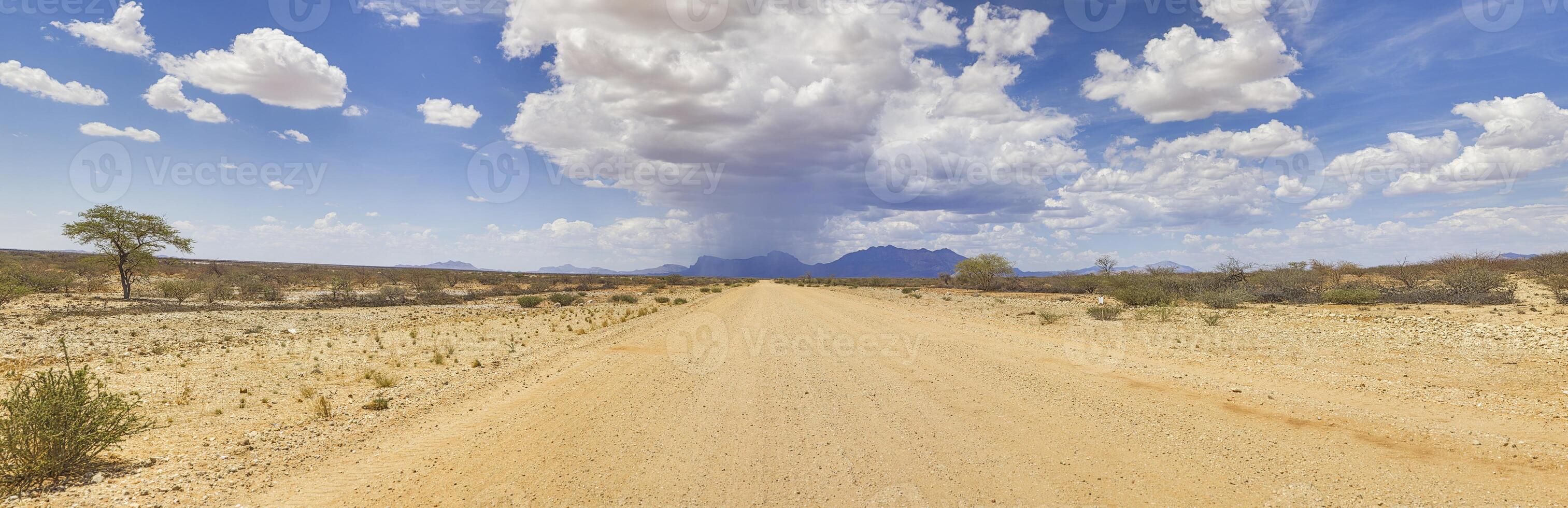 panoramisch afbeelding over- een grind weg in damaraland gedurende de regenachtig seizoen met storm wolken foto