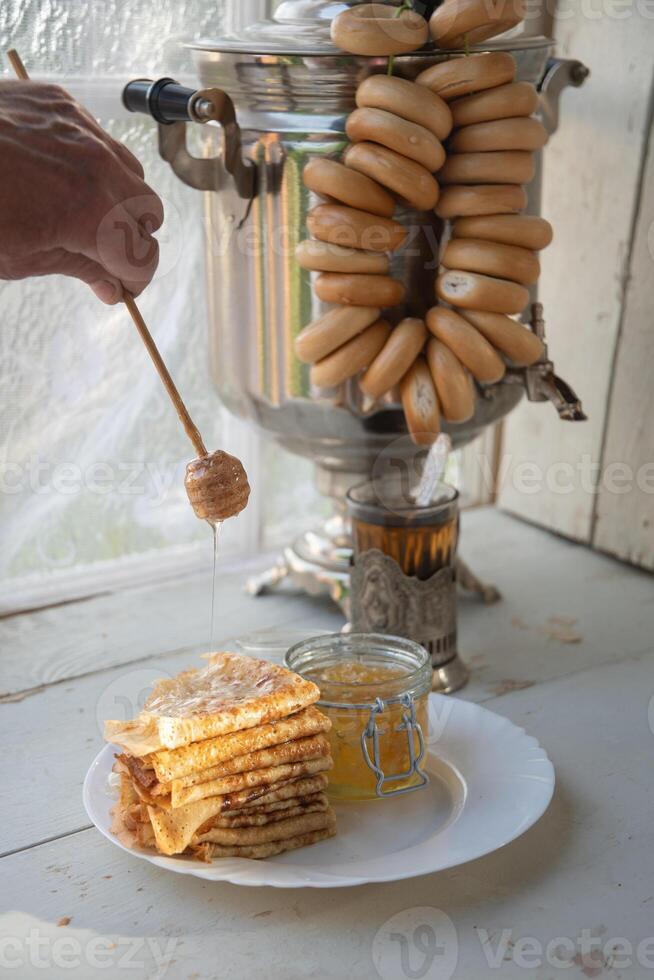 Russisch pannekoeken met honing en een kop van thee van een wijnoogst Samowar maslenitsa festival concept foto