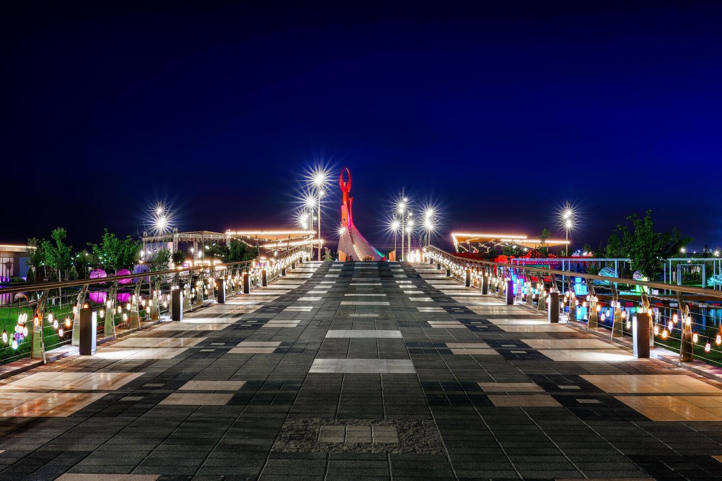 Oezbekistan, Tasjkent - april 25, 2023 verlichte monument van onafhankelijkheid in de het formulier van een stele met een humo vogel in de nieuw Oezbekistan park Bij nacht. visie van de brug. foto
