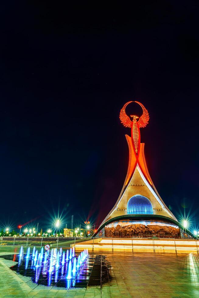 Oezbekistan, Tasjkent - april 25, 2023 verlichte monument van onafhankelijkheid in de het formulier van een stele met een humo vogel in de nieuw Oezbekistan park Bij nacht. foto