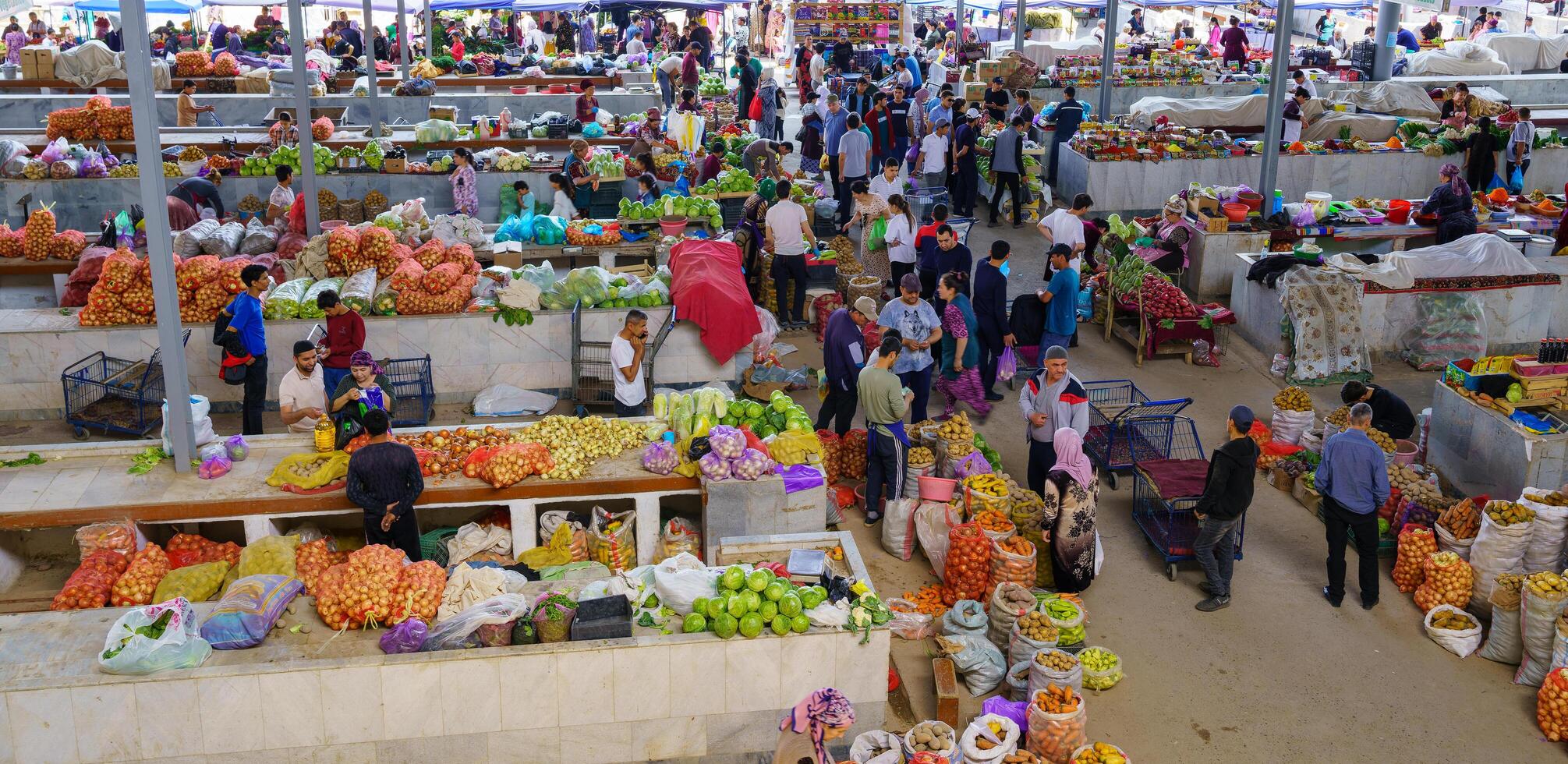 samarkand, Oezbekistan - april 27, 2023 top visie van rijen van fruit en groente kraampjes en verkoper in een oosters bazaar in centraal Azië. foto