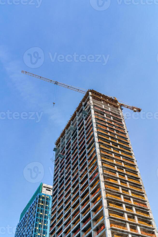 een kraan gebouw een wolkenkrabber tegen een blauw lucht. foto