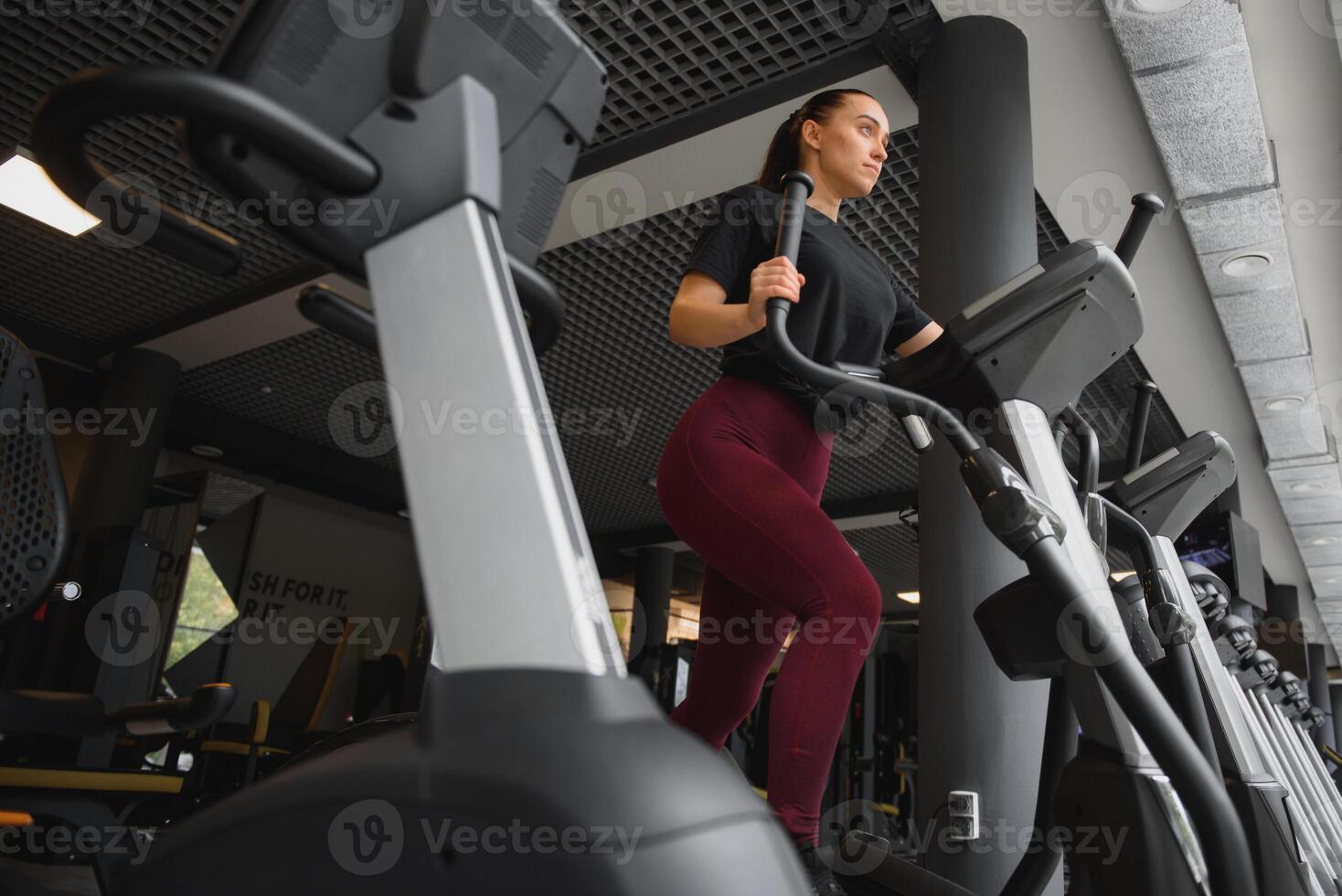 aantrekkelijk jong vrouw loopt Aan een loopband, is verloofd in geschiktheid sport club. foto