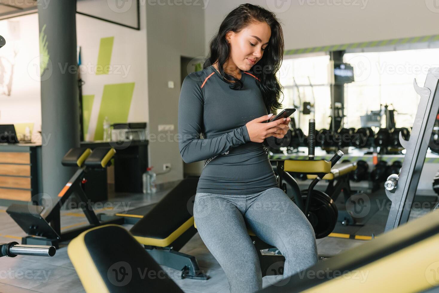 prachtig jong vrouw sms'en en sociaal netwerken terwijl in een Sportschool. foto