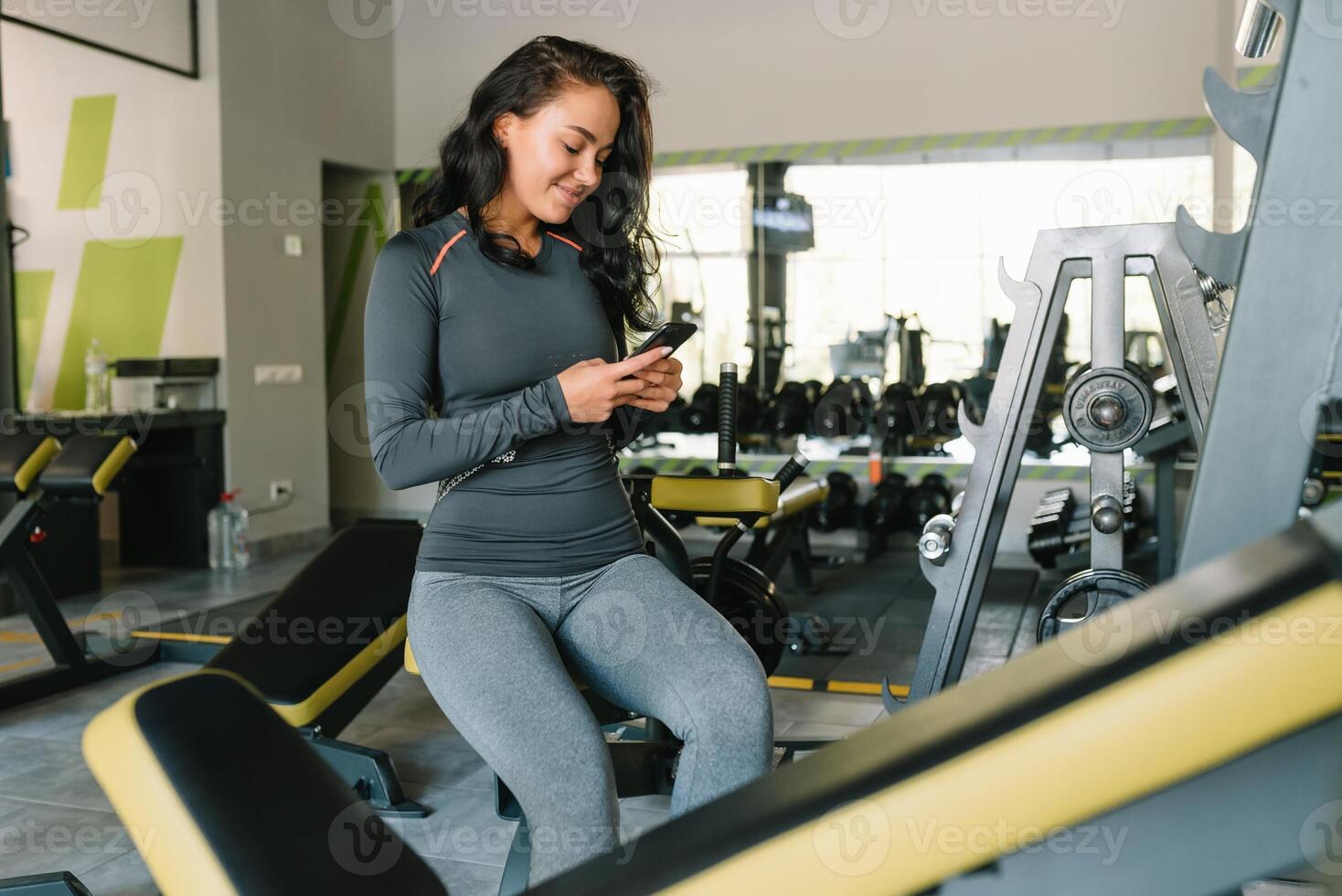 prachtig jong vrouw sms'en en sociaal netwerken terwijl in een Sportschool. foto