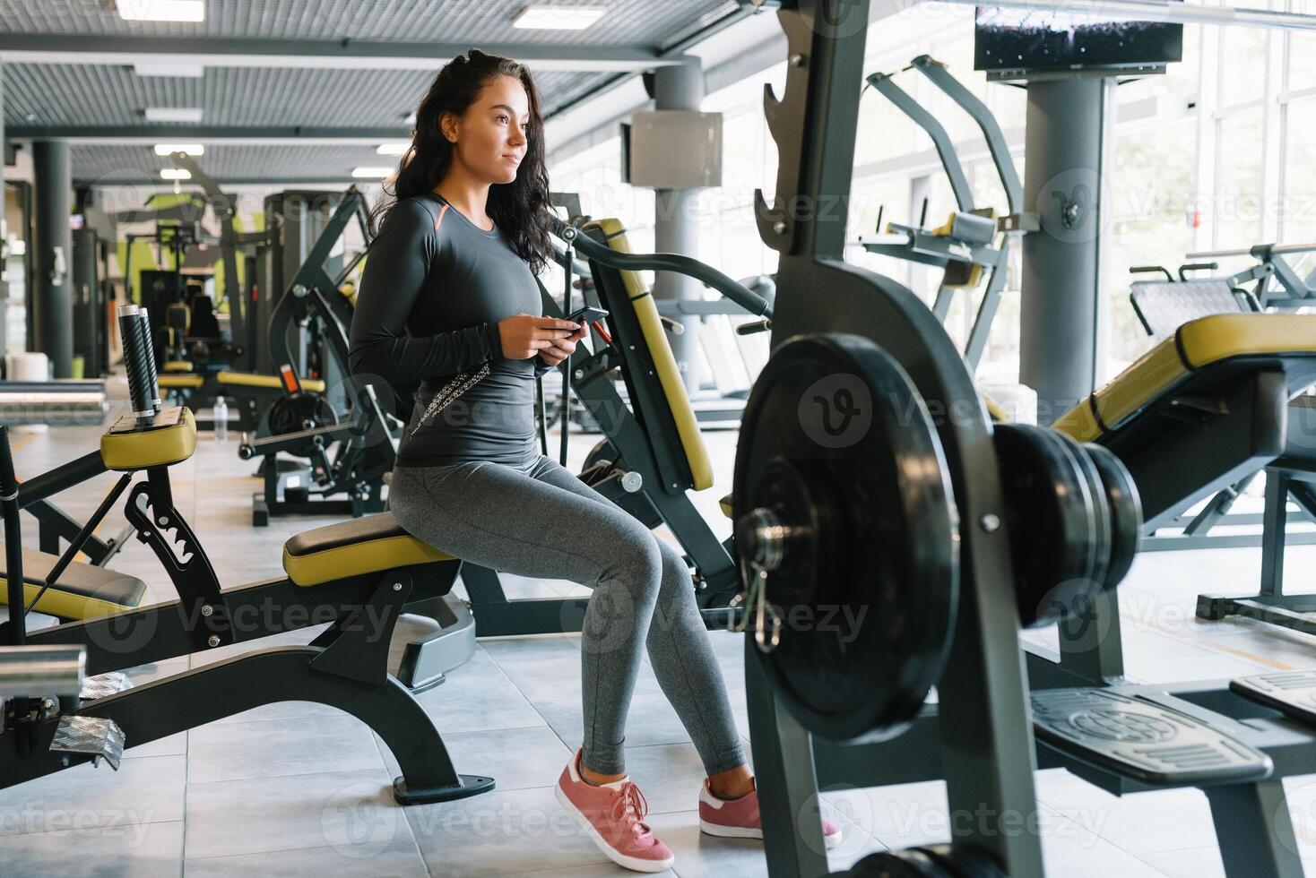 prachtig jong vrouw sms'en en sociaal netwerken terwijl in een Sportschool. foto