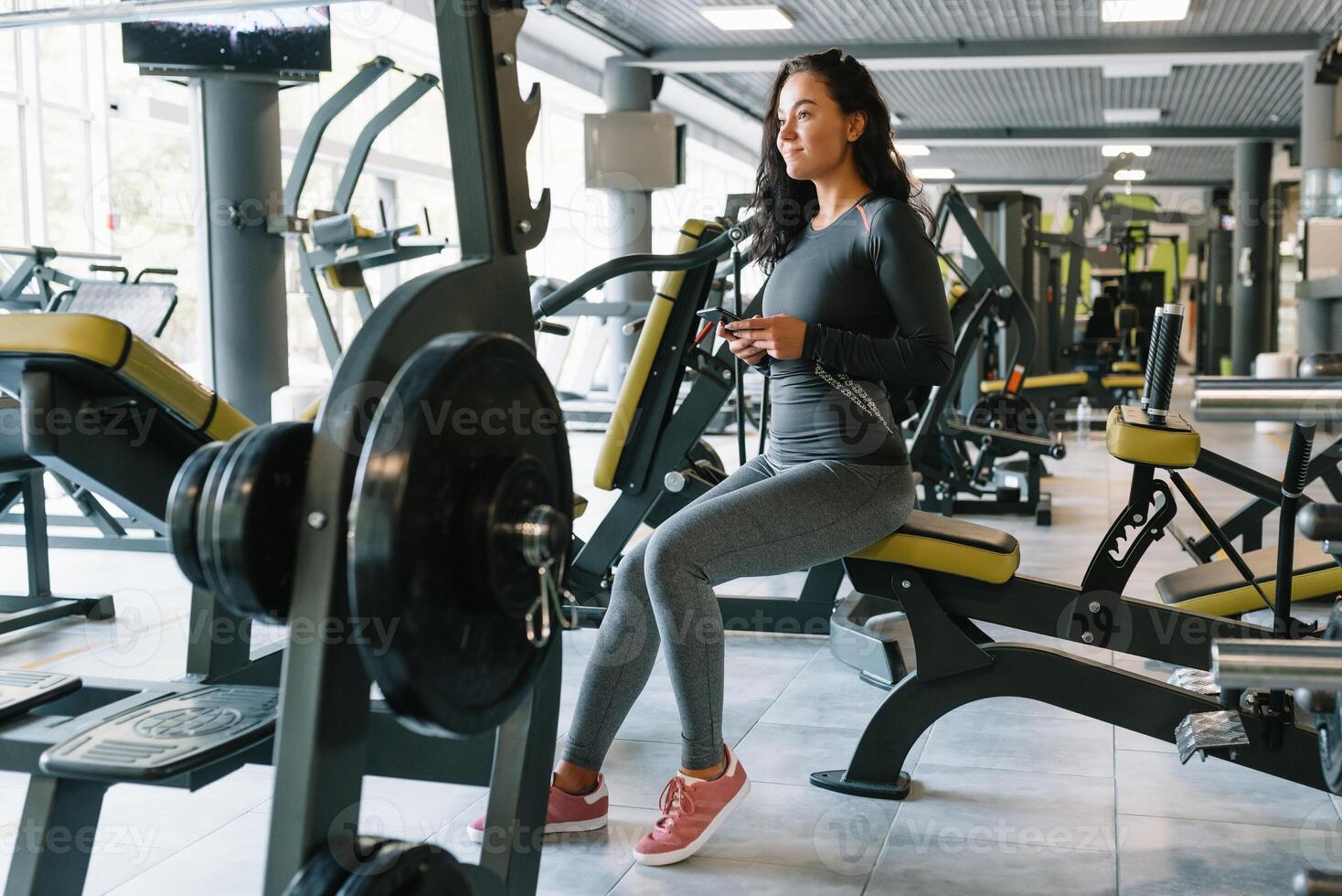 prachtig jong vrouw sms'en en sociaal netwerken terwijl in een Sportschool. foto