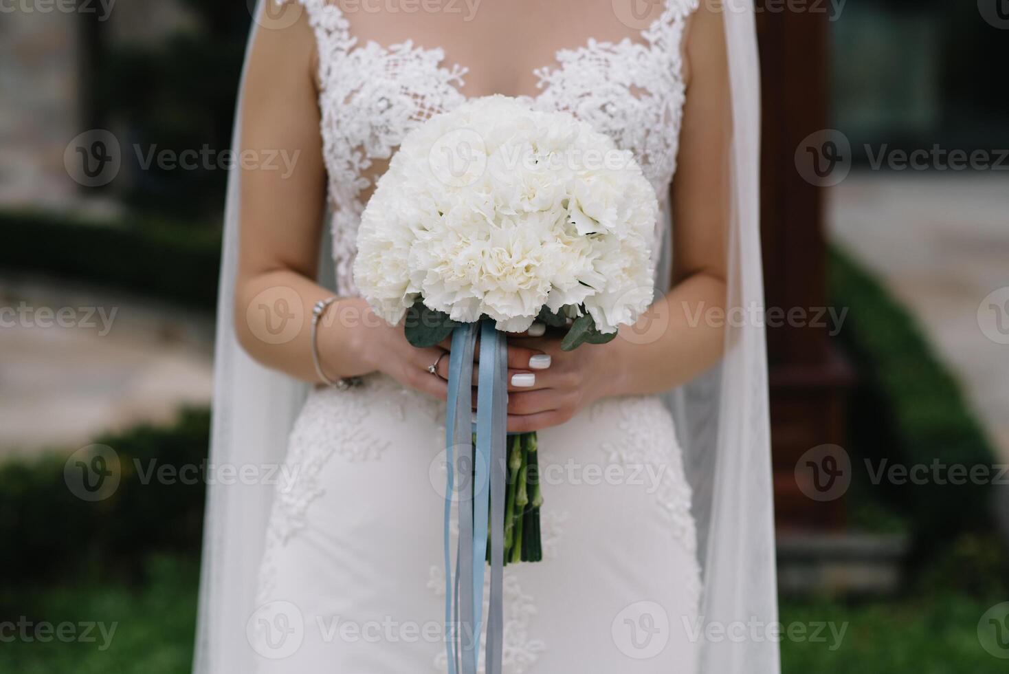 bruid staat in een wit bruiloft jurk met een boeket van bloemen foto