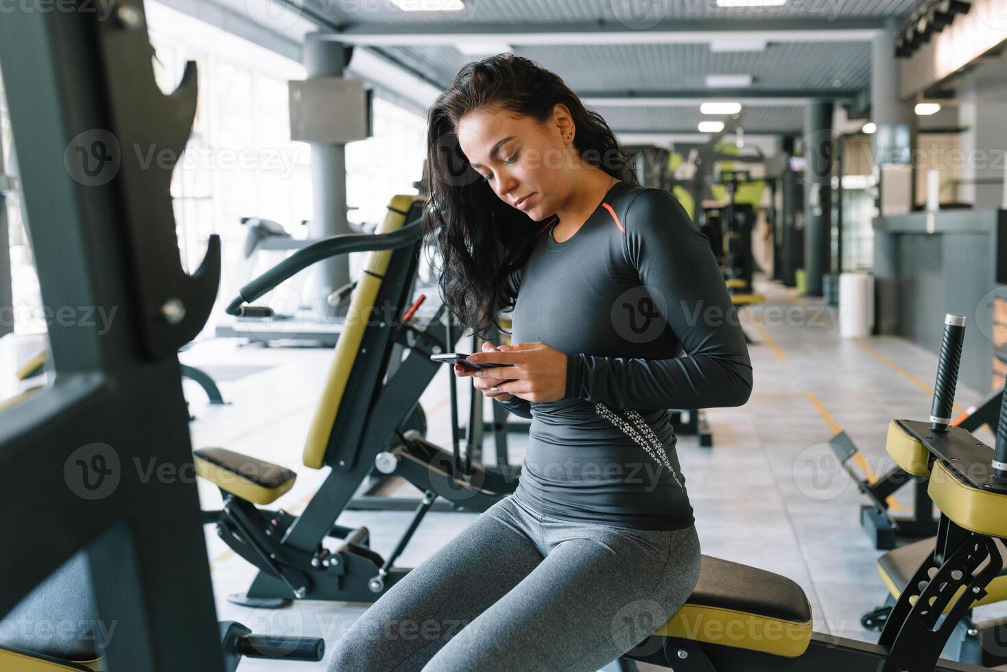 prachtig jong vrouw sms'en en sociaal netwerken terwijl in een Sportschool. foto