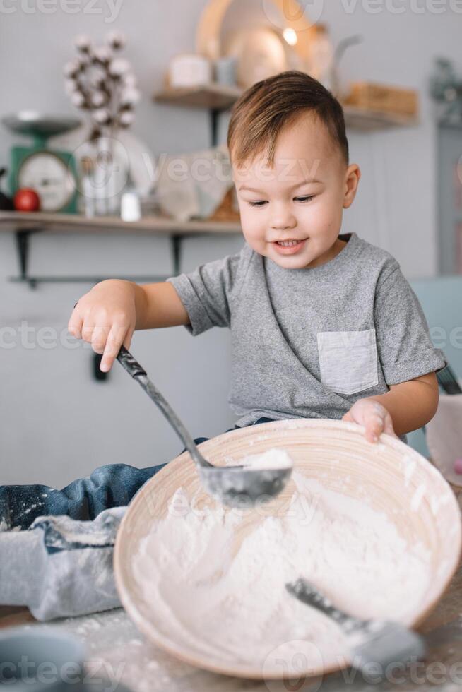 jong jongen schattig Aan de keuken koken chef in wit uniform en hoed in de buurt tafel. eigengemaakt ontbijtkoek. de jongen gekookt de chocola koekjes. foto