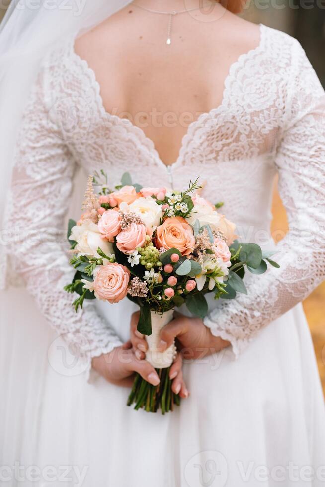 bruid staat in een wit bruiloft jurk met een boeket van bloemen. foto