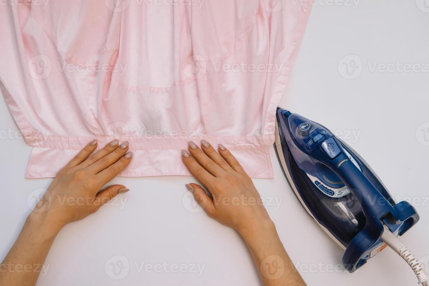 vrouw hand- strijken kleren top visie geïsoleerd Aan wit achtergrond. jong vrouw met ijzer strijken man's overhemd gezien van bovenstaand gedurende huiswerk. blauw ijzer Aan wit tafel foto