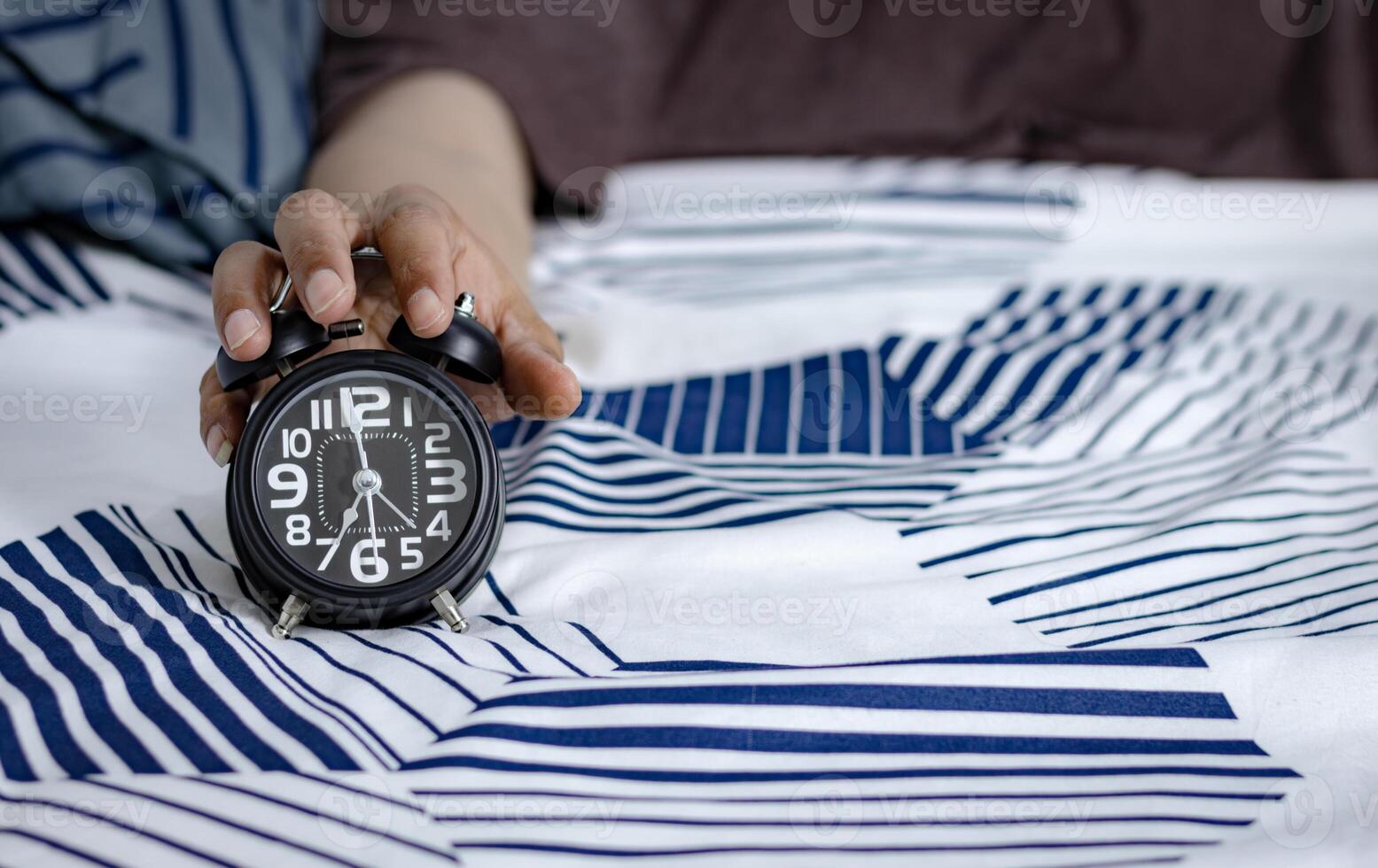 deadline en tijd beheer concept. Mens handen Holding zwart alarm klok Aan bed. tijd naar wakker worden omhoog voor de ochtend- routine- foto