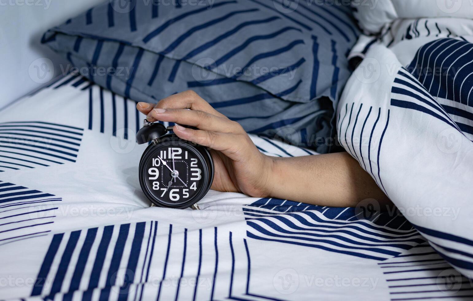 deadline en tijd beheer concept. Mens handen Holding zwart alarm klok Aan bed. tijd naar wakker worden omhoog voor de ochtend- routine- foto