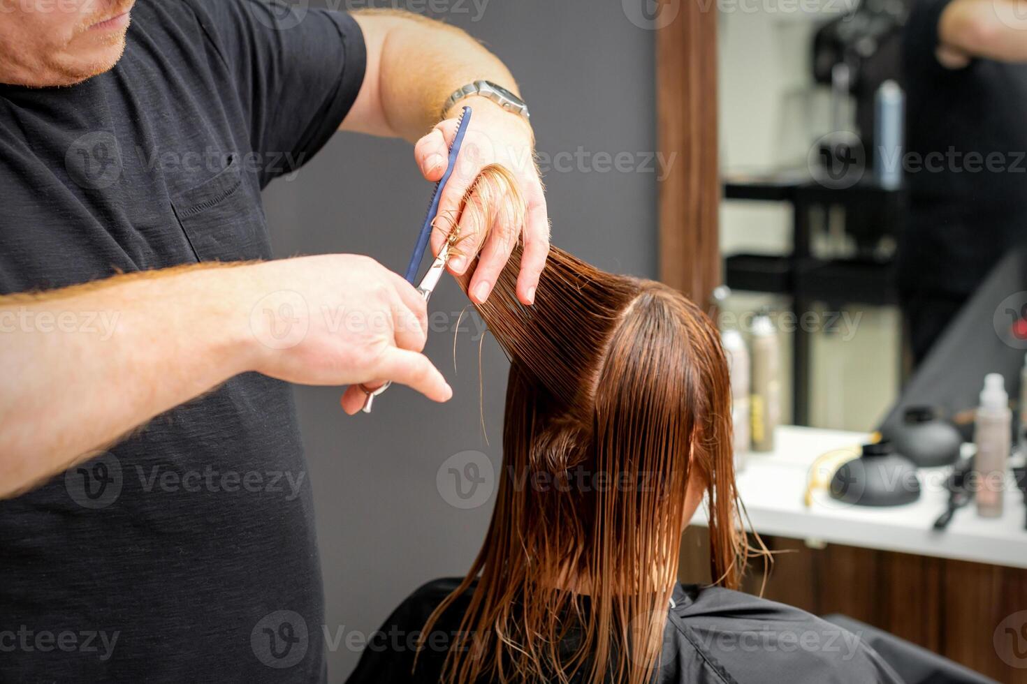 vrouw hebben een nieuw kapsel. mannetje haar stylist snijdend bruin haar- met schaar in een haar- salon. foto