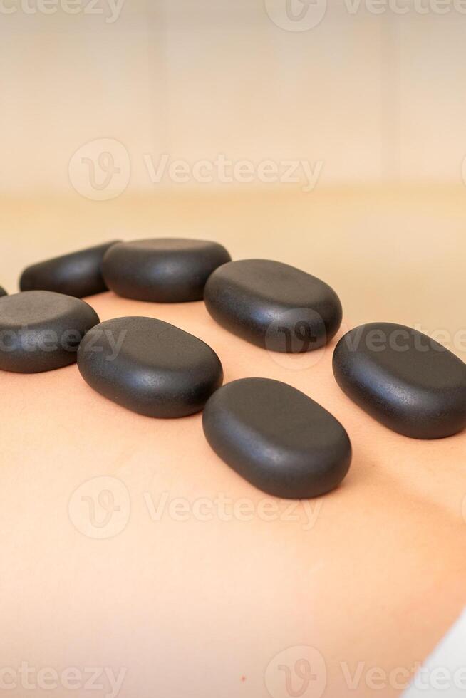 heet steen massage therapie. Kaukasisch jong Mens krijgen een heet steen massage Aan terug Bij spa salon. foto