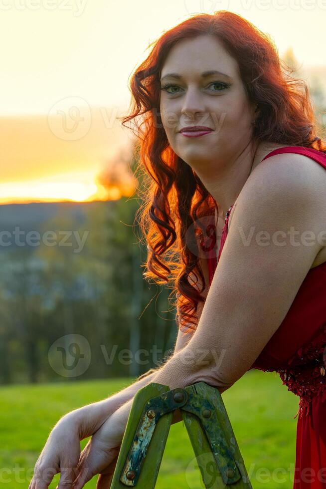 vrouw in een rood jurk en een ladder in een zonsondergang foto