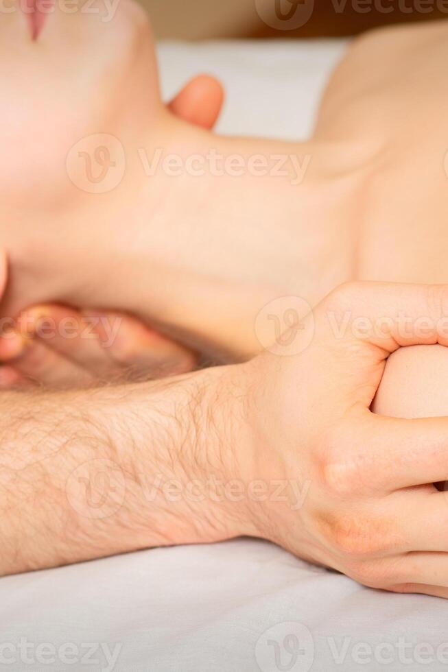 mannetje masseur masseren schouder van een jong vrouw aan het liegen Aan een massage tafel in een spa kliniek. foto