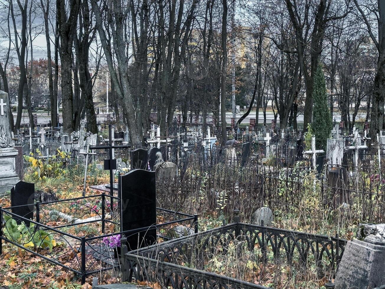 somber begraafplaats, begraafplaats met grafstenen, kruisen en bomen foto