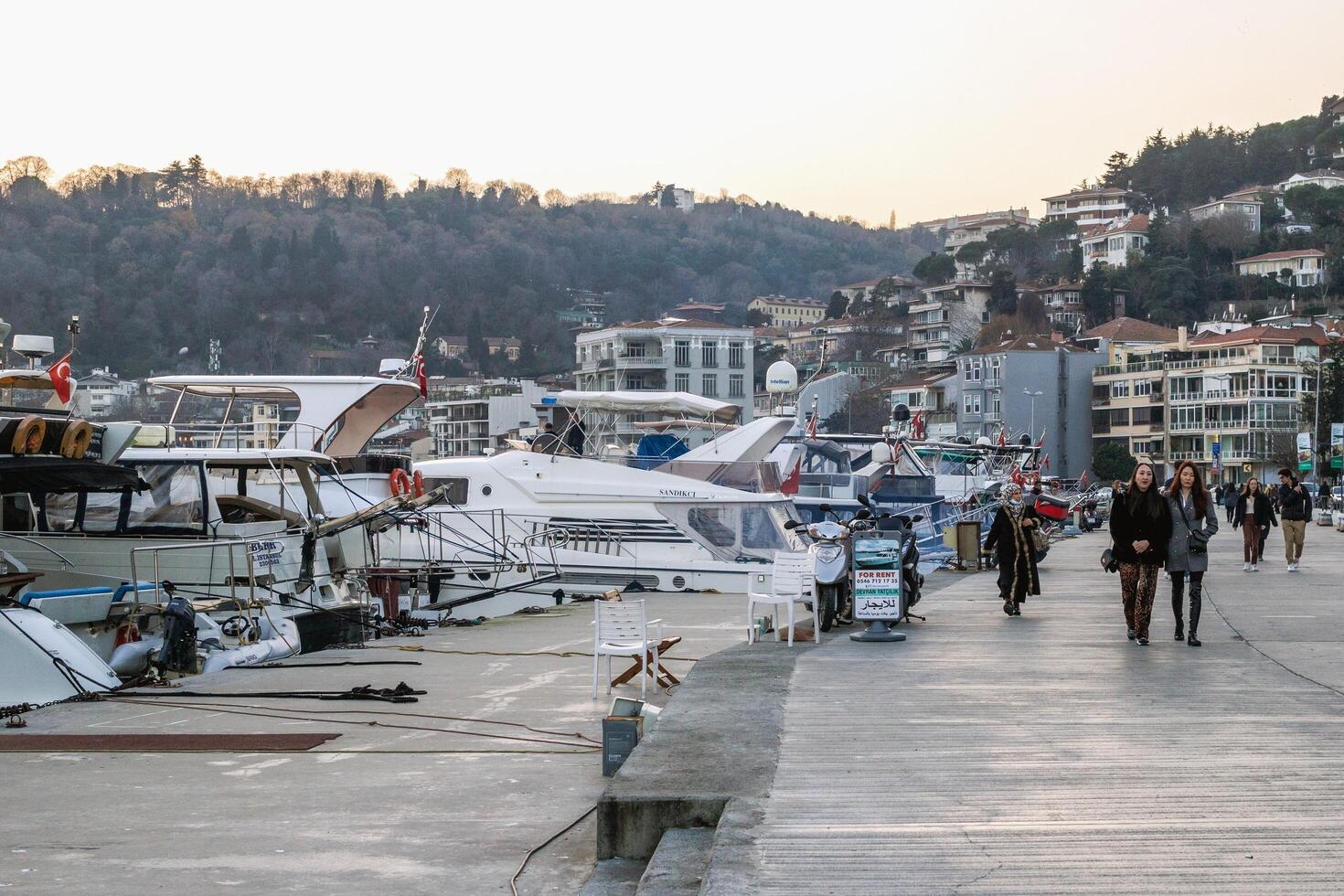 Istanbul, kalkoen - december 29, 2023. toneel- stadsgezicht met haven, boten aangemeerd, en mensen genieten van loopbrug door de pier. foto