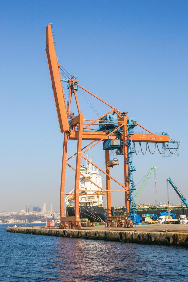 Istanbul, kalkoen - december 29, 2022. groot industrieel haven kraan in werking in de haven onder Doorzichtig blauw lucht. foto