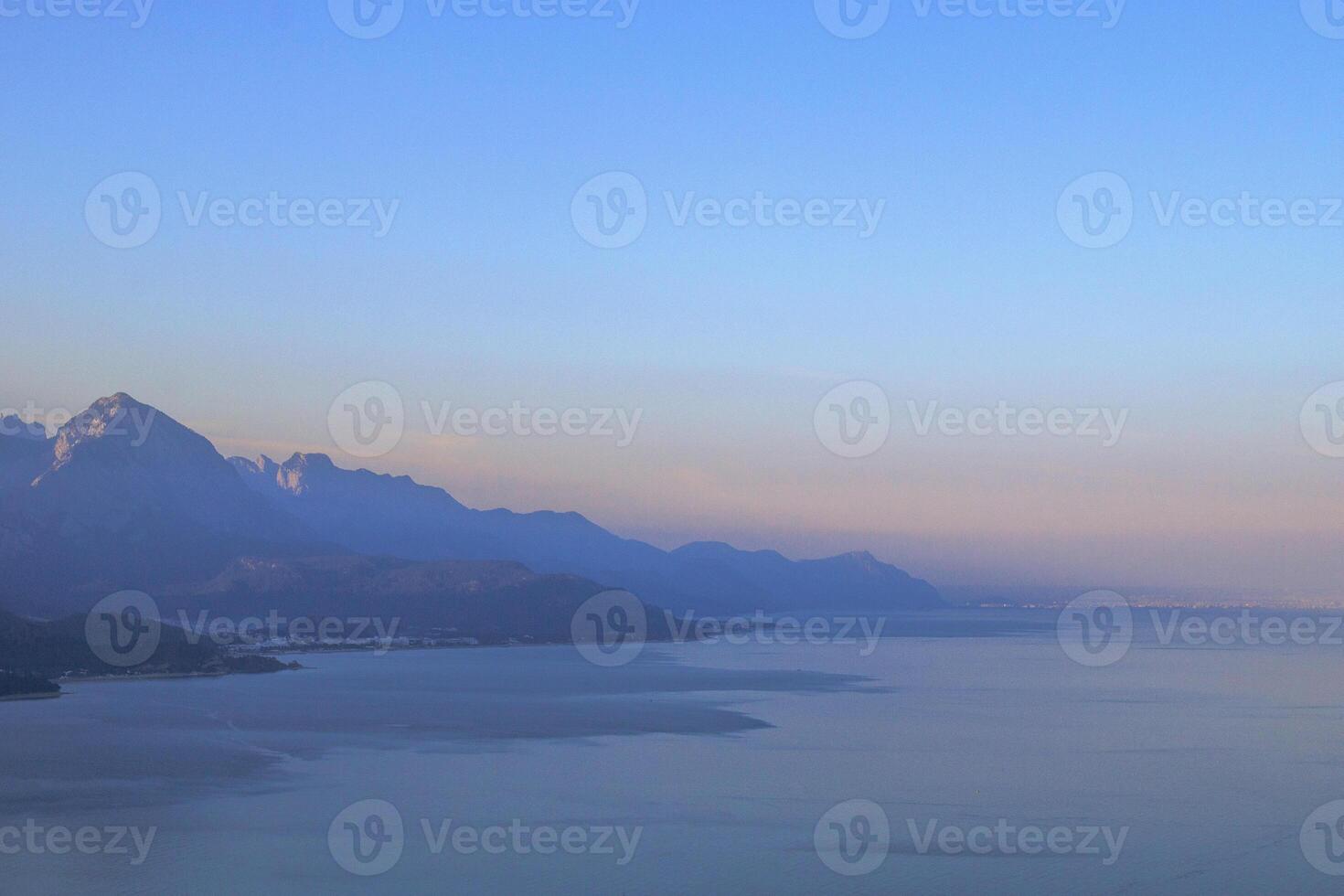rustig zeegezicht met ver weg berg bereik, Doorzichtig blauw lucht, en sereen atmosfeer. foto
