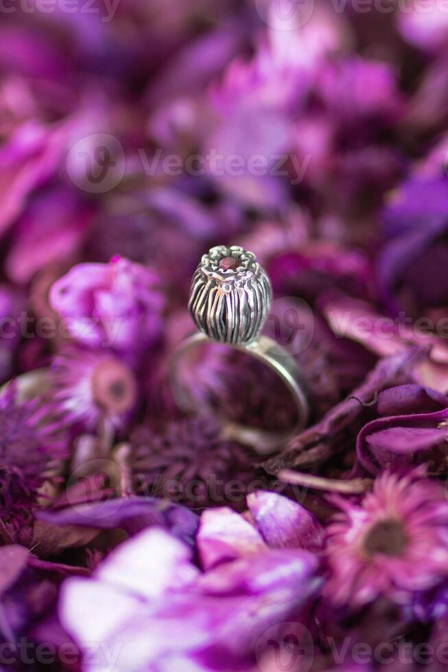 mooi zilver ring met roze steen Aan een achtergrond van droog Purper bloemen. handgemaakt kostbaar item. foto