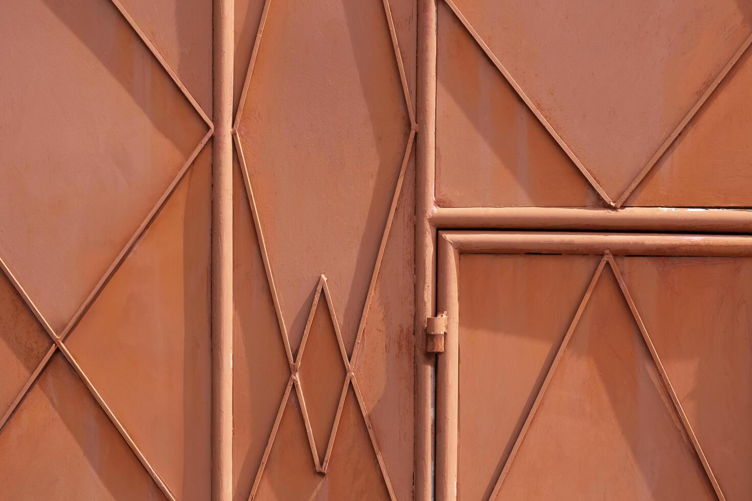 achtergrond en structuur van de oud oranje metaal poort deur van machine werkplaats met meetkundig lijnen patroon Aan oppervlakte foto