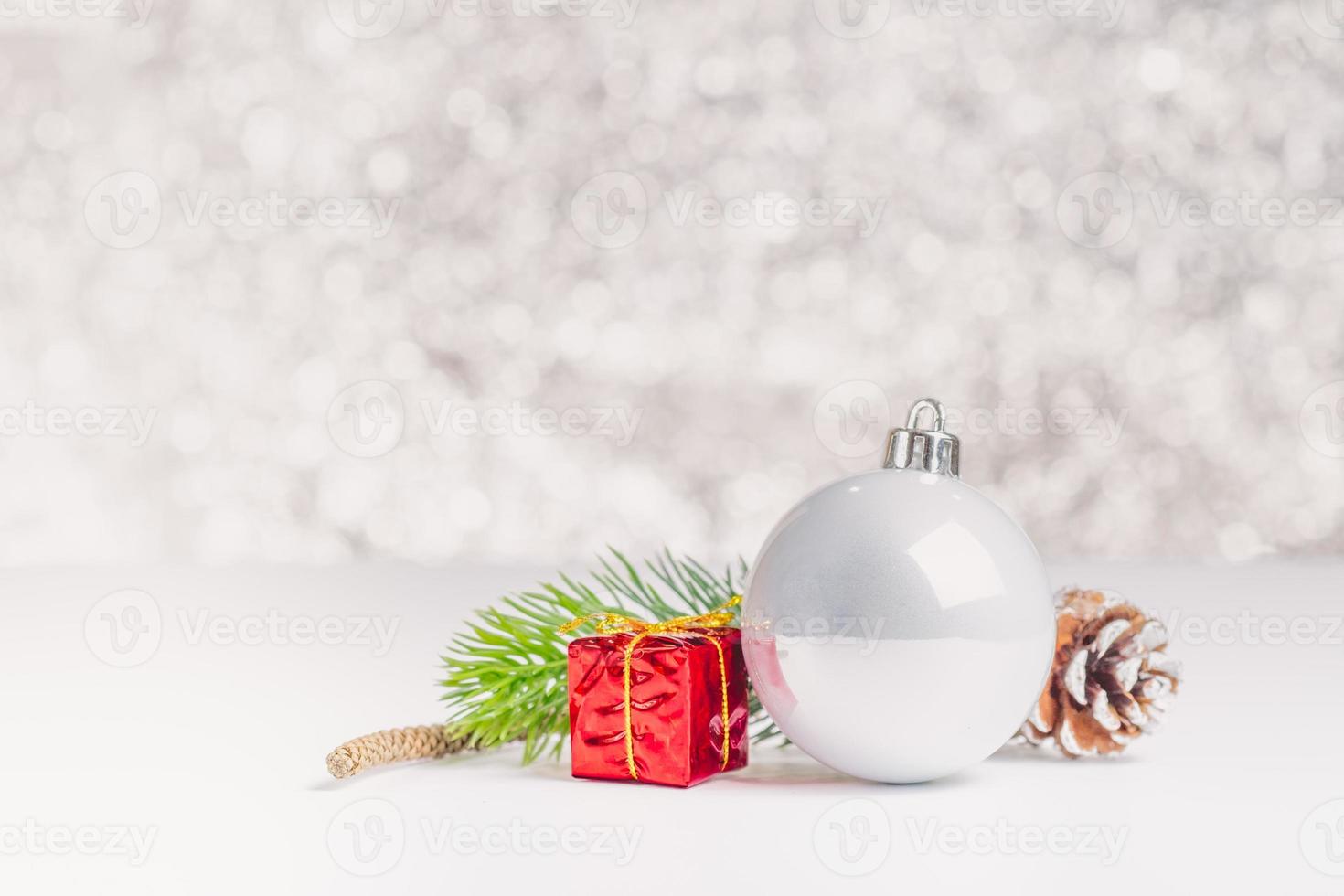 witte kerst glanzende bal en geschenkdoos op witte tafel bij sprankelende blauwe bokeh foto