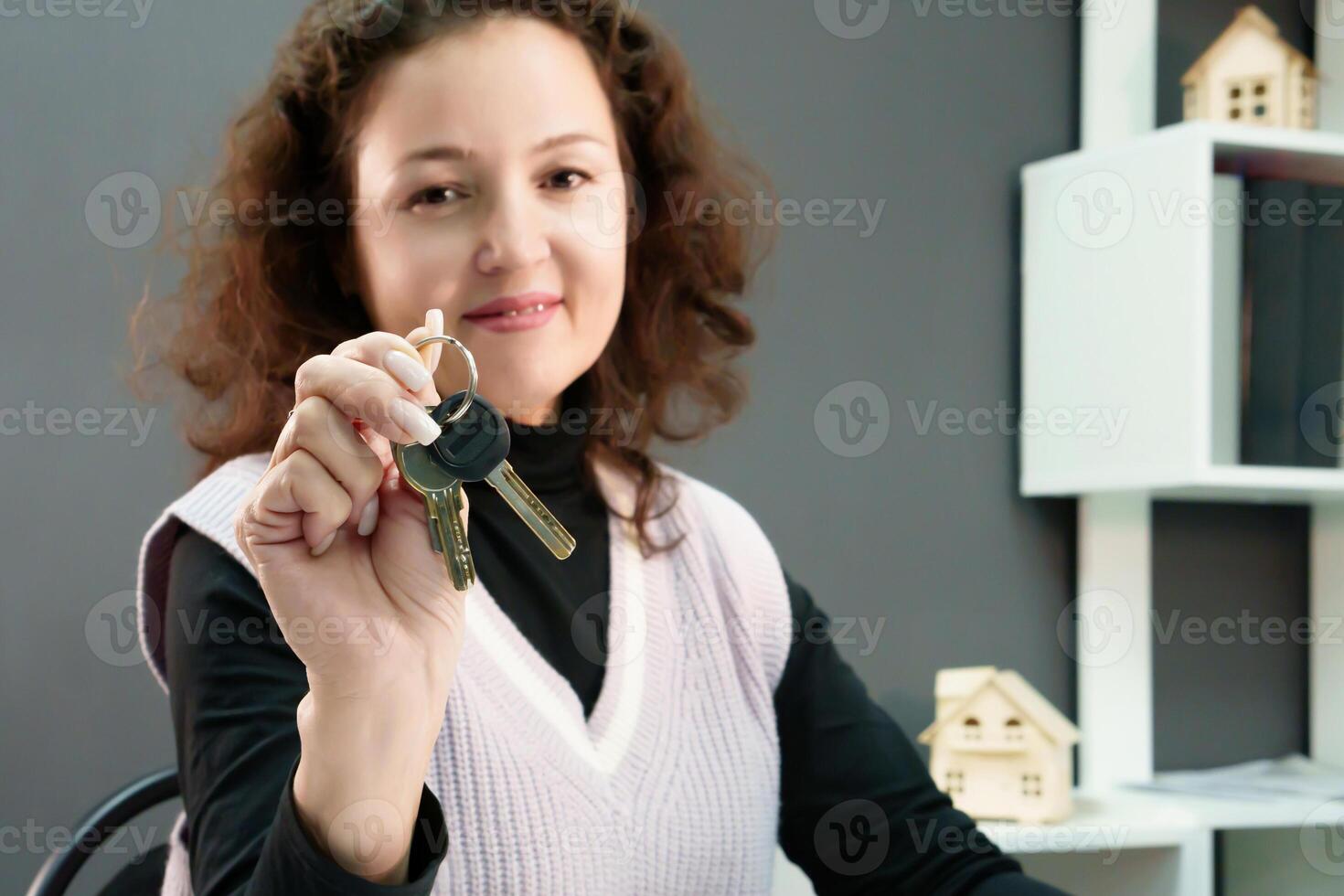 glimlachen makelaar met gekruld haar- en sleutels in hand, klaar naar aanbod haar echt landgoed Diensten en aantrekken nieuw klanten foto