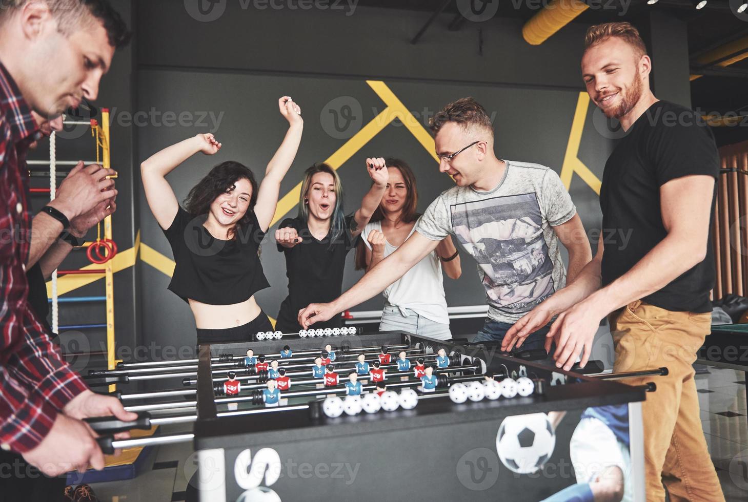 lachende jonge mensen die tafelvoetbal spelen terwijl ze op vakantie zijn foto