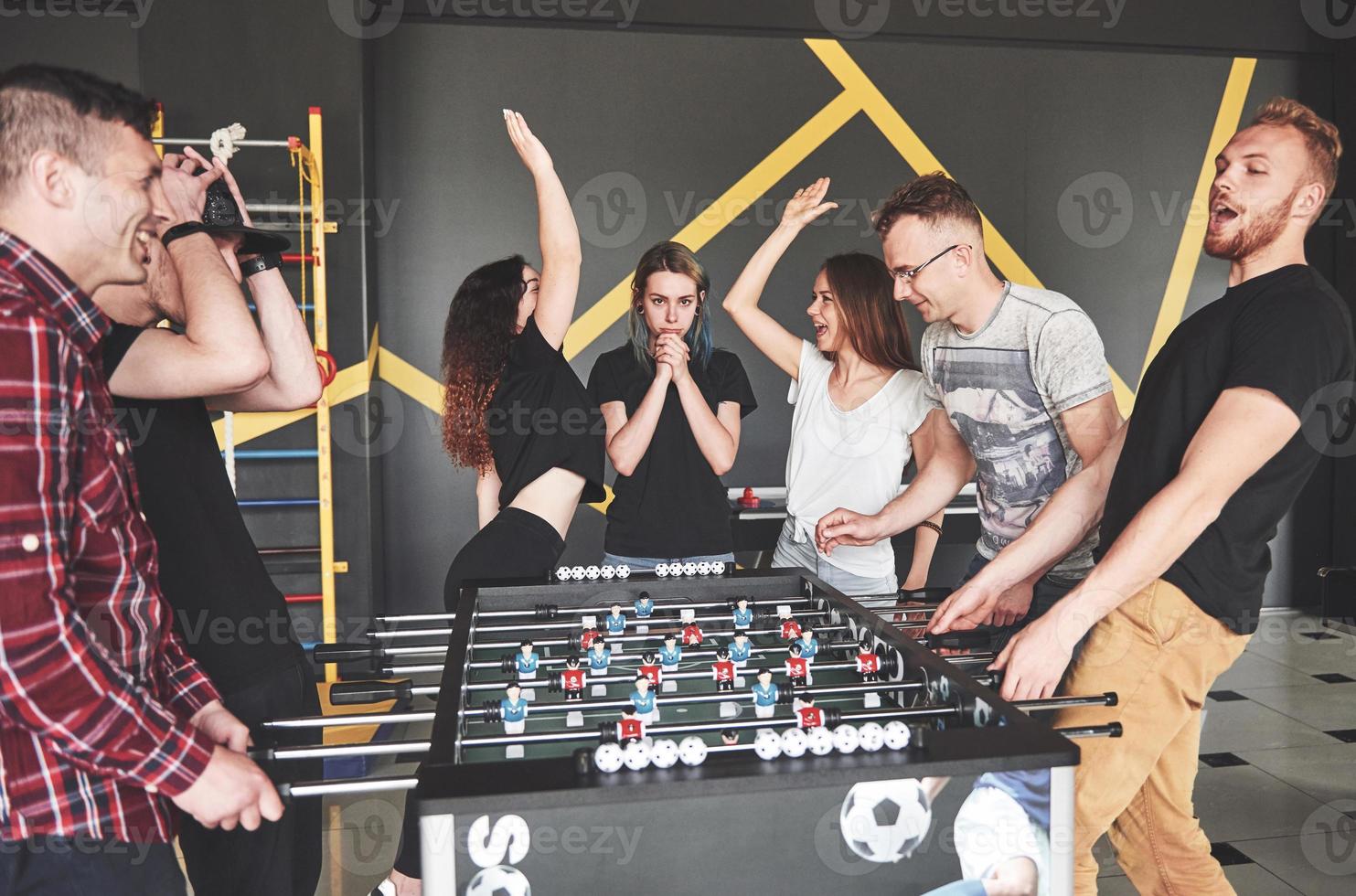 lachende jonge mensen die tafelvoetbal spelen terwijl ze op vakantie zijn foto