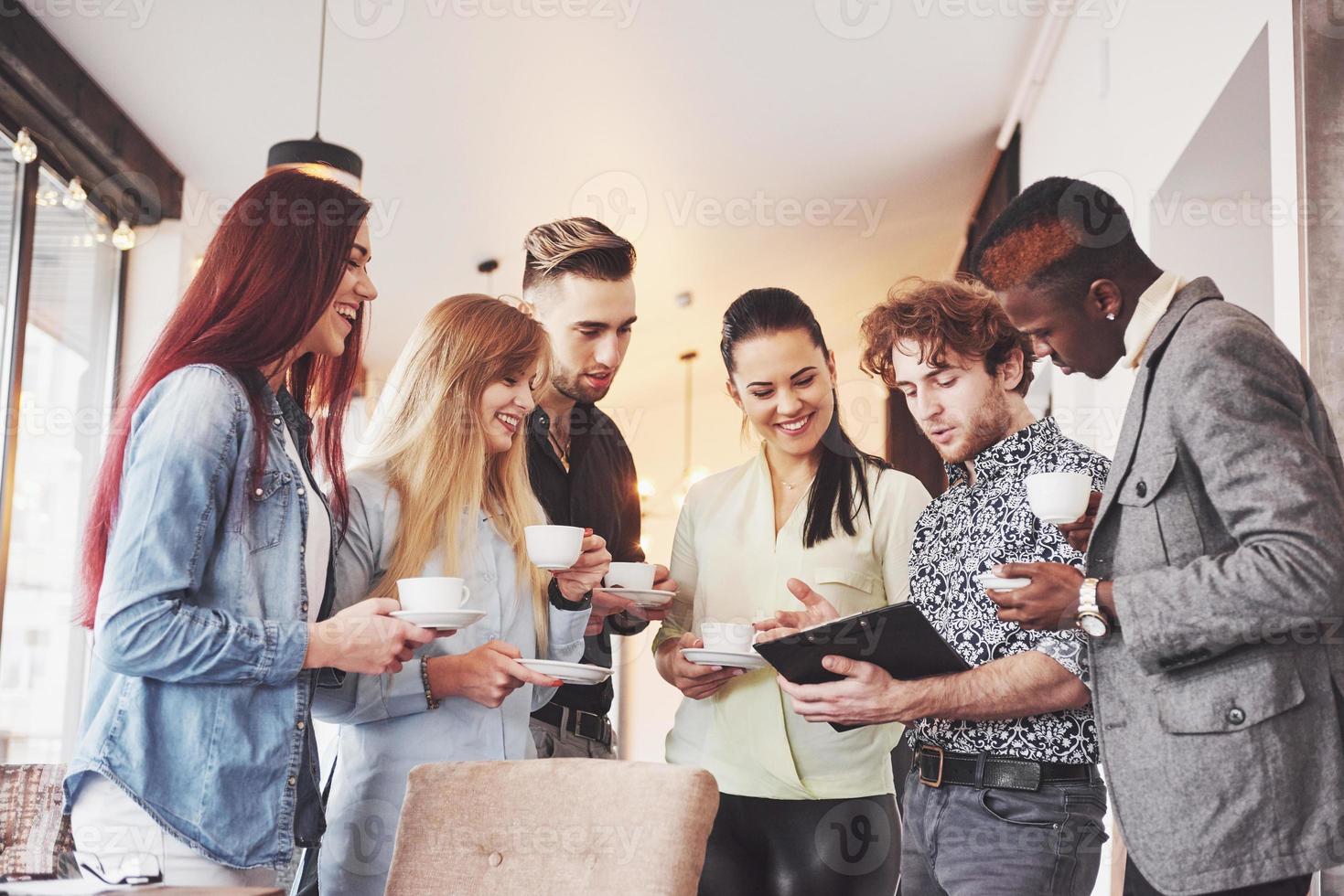 succesvolle zakenmensen gebruiken gadgets, praten en glimlachen tijdens de koffiepauze op kantoor foto