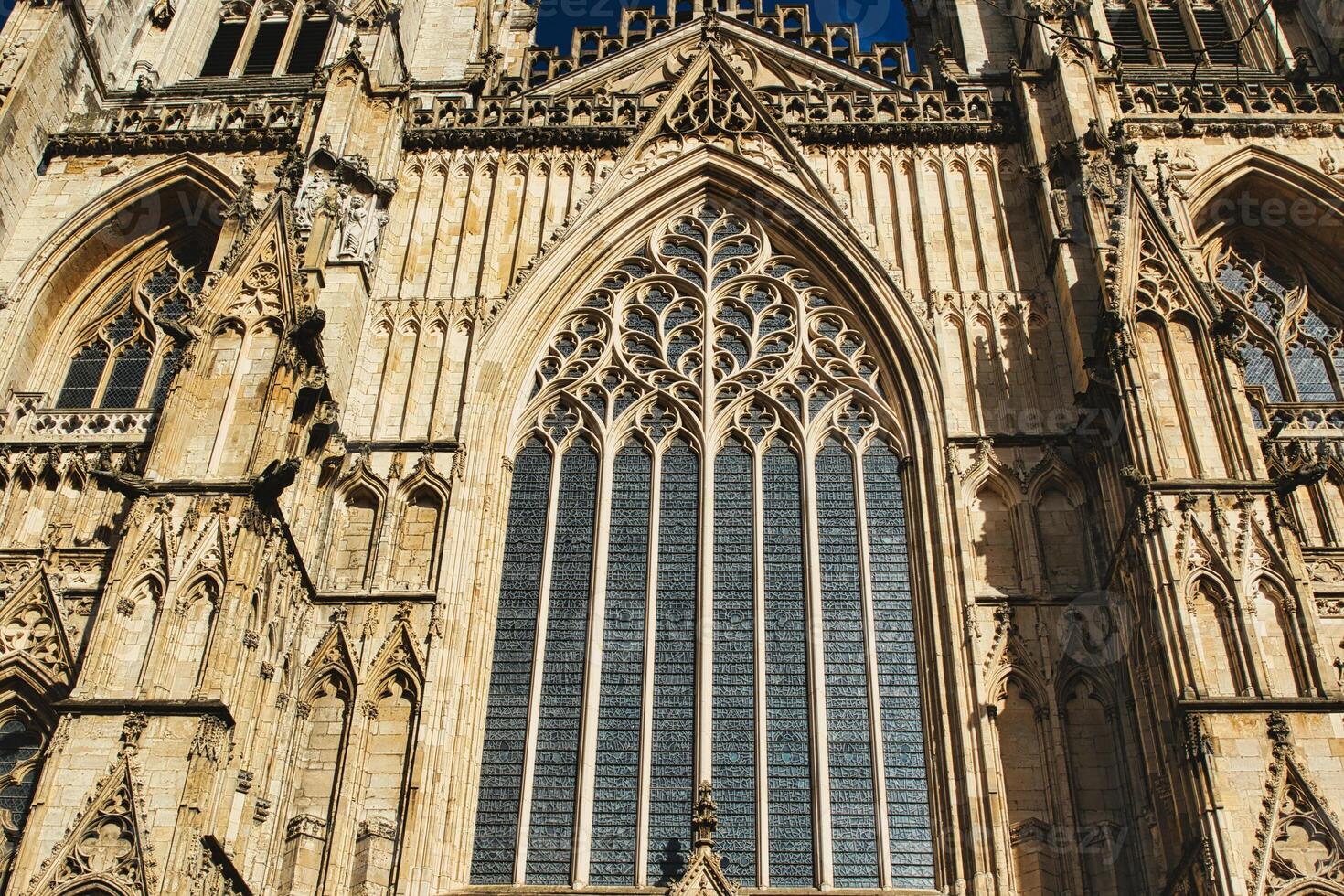 gotisch architectuur detail van een kathedraal facade, met een groot gebrandschilderd glas venster en overladen steen houtsnijwerk onder Doorzichtig luchten in york, noorden yorkshire, Engeland. foto