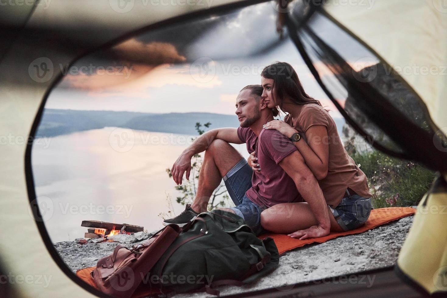 uitzicht vanuit tent van paar liggend op het meer tijdens wandeltocht. avel lifestyle concept avontuurlijke vakanties buiten foto