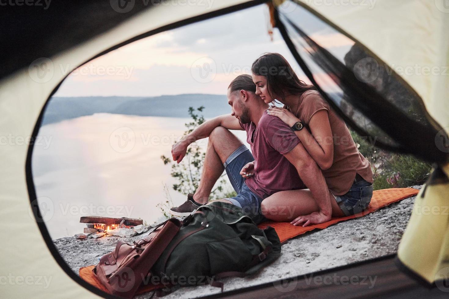 uitzicht vanuit tent van paar liggend op het meer tijdens wandeltocht. avel lifestyle concept avontuurlijke vakanties buiten foto